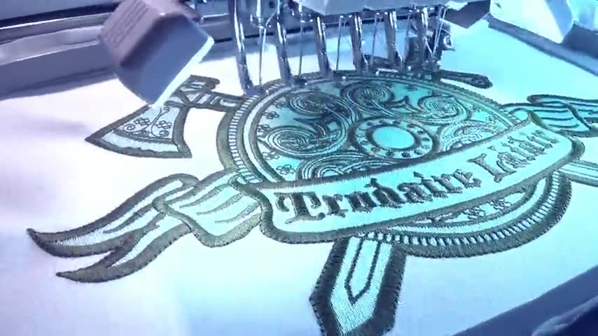 Silent loop of three embroidered patches being stitched on commercial machines at Independence Embroidery in Missouri.